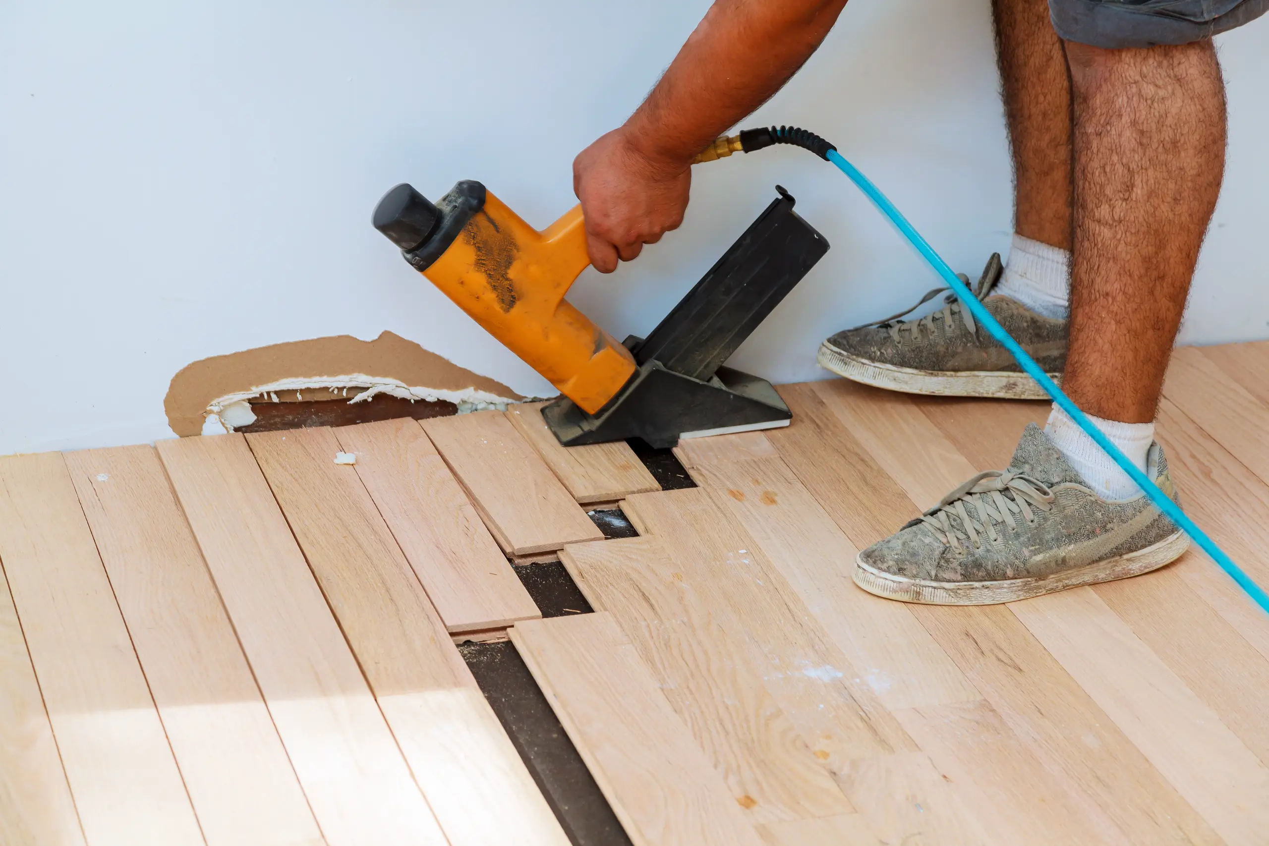 Ein Handwerker verlegt Holzplatten auf dem Boden mit einer speziellen Werkzeugmaschine