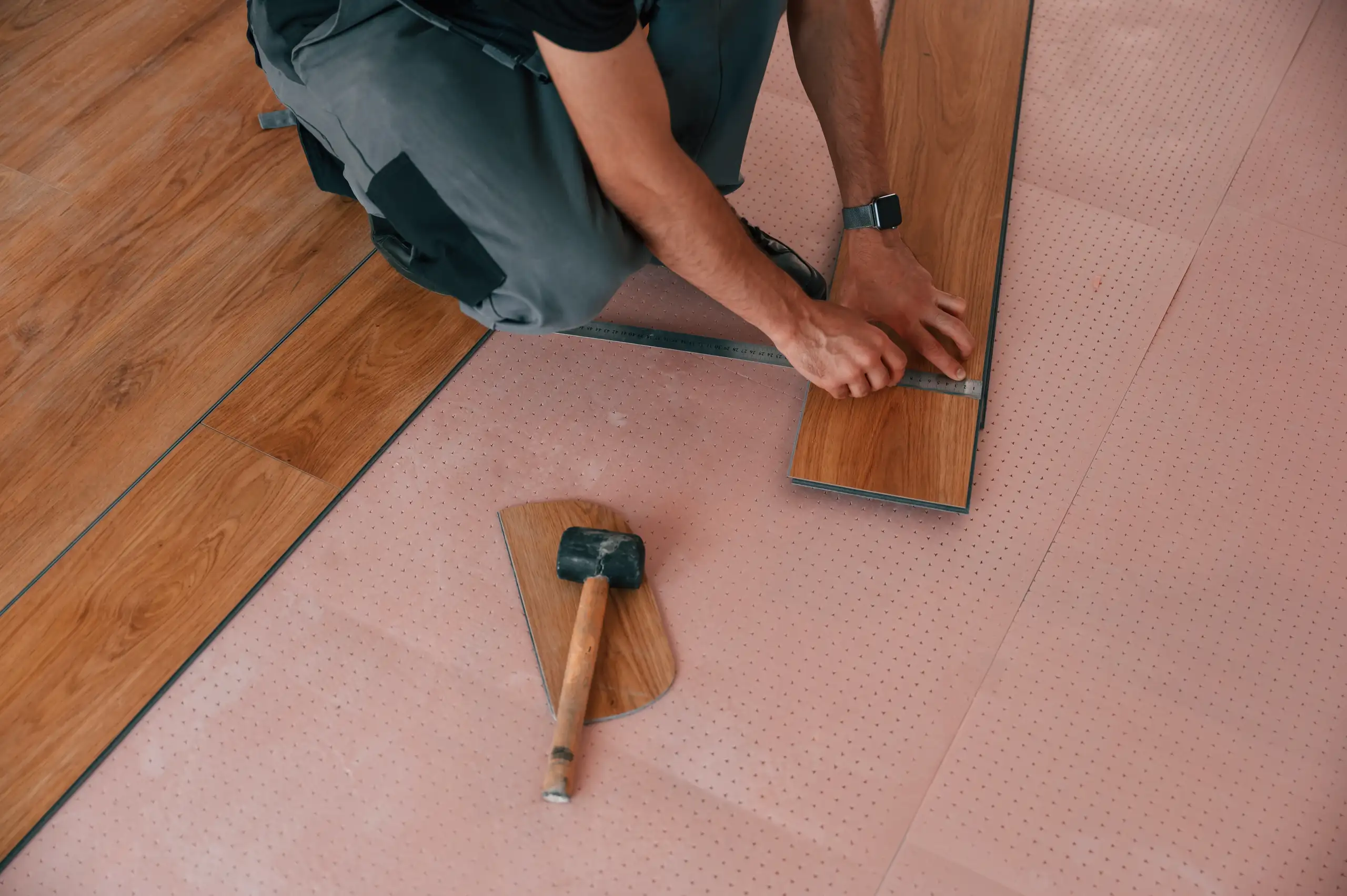 Mitarbeiter verlegt Terrassendielen mit präziser Handarbeit